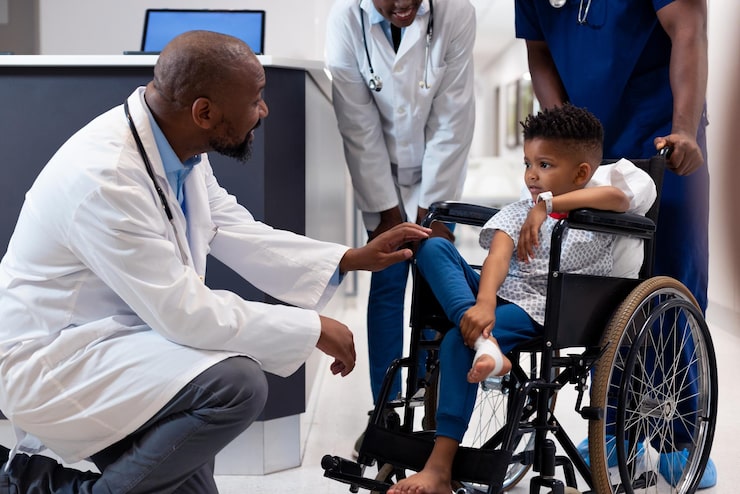 smiling african american male doctor talking boy patient wheelchair corridor hospital medical healthcare services_13339 337891 1